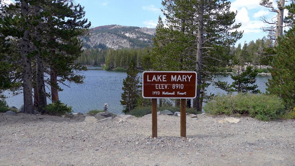 A photo of a sign in front of a lake saying "Lake Mary Elev. 8910 Inyo National Forest"