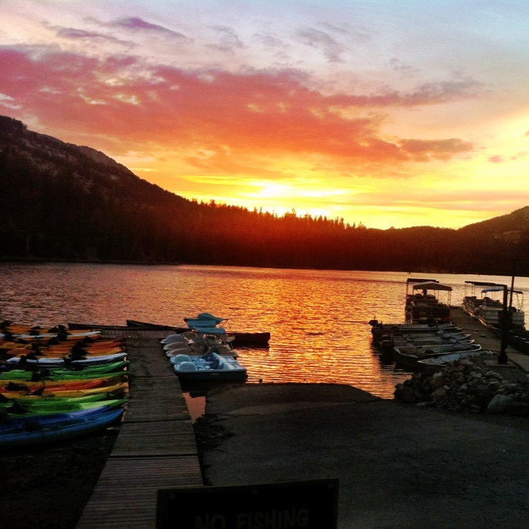 Photo of a sunset on a lake with boats on a dock