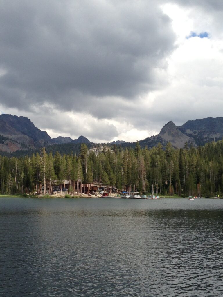 A photo of buildings (Lake Mary Marina) with a forest and mountains behind and a lake and docks in front