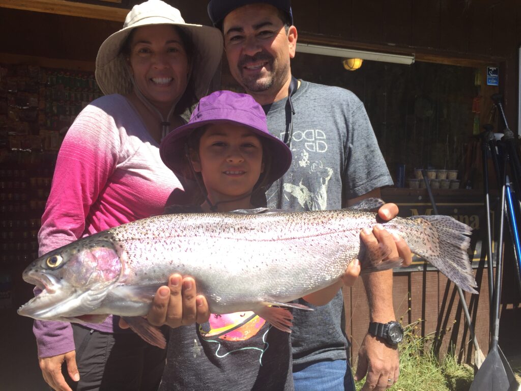 A family of three, with the child holding a trout