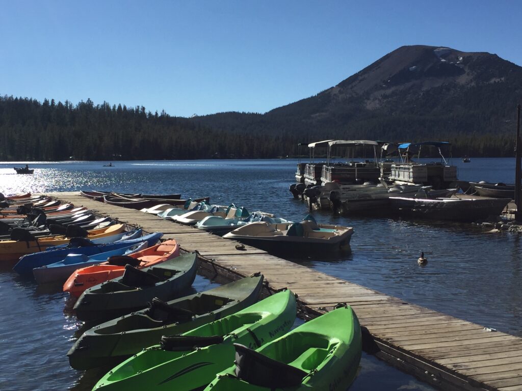 A photo of a dock with kayaks and pontoon boats