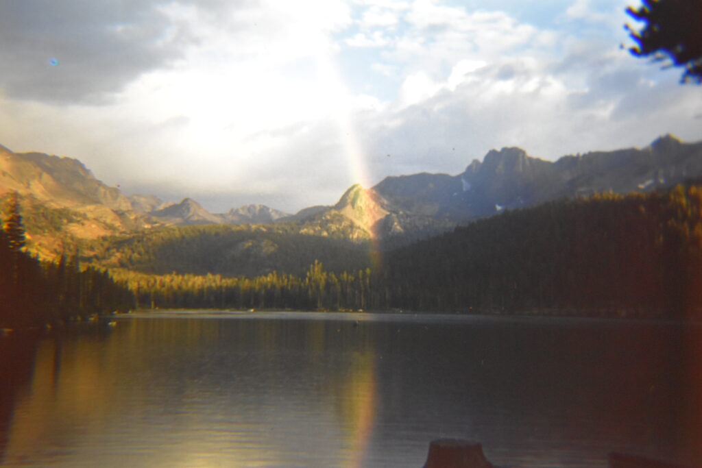 Photo from the 1960s on a rainbow coming through the clouds on to the lake