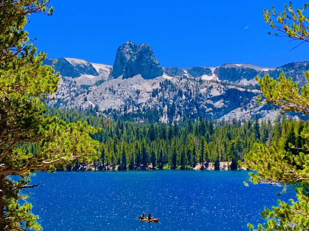 Photo of two people kayaking on a lake with mountains in background