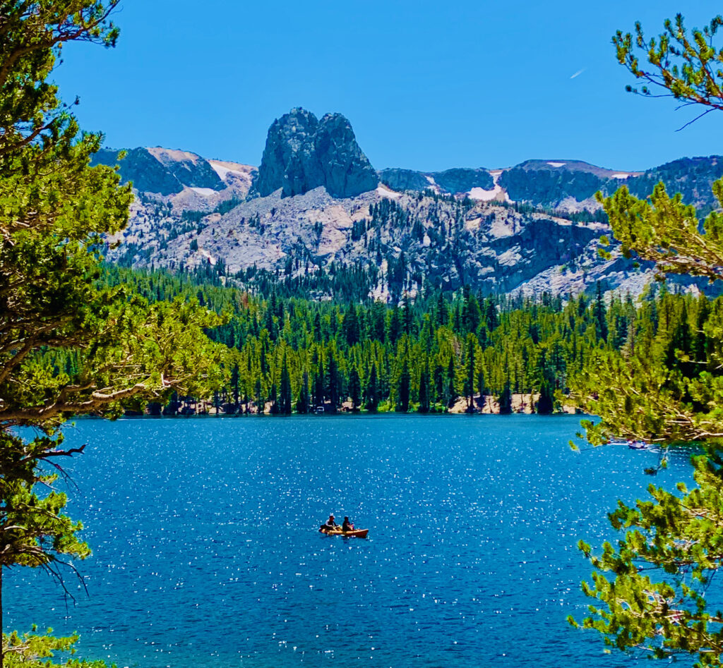 Photo of a lake (Lake Mary) with two people kayaking on it and mountains in the background